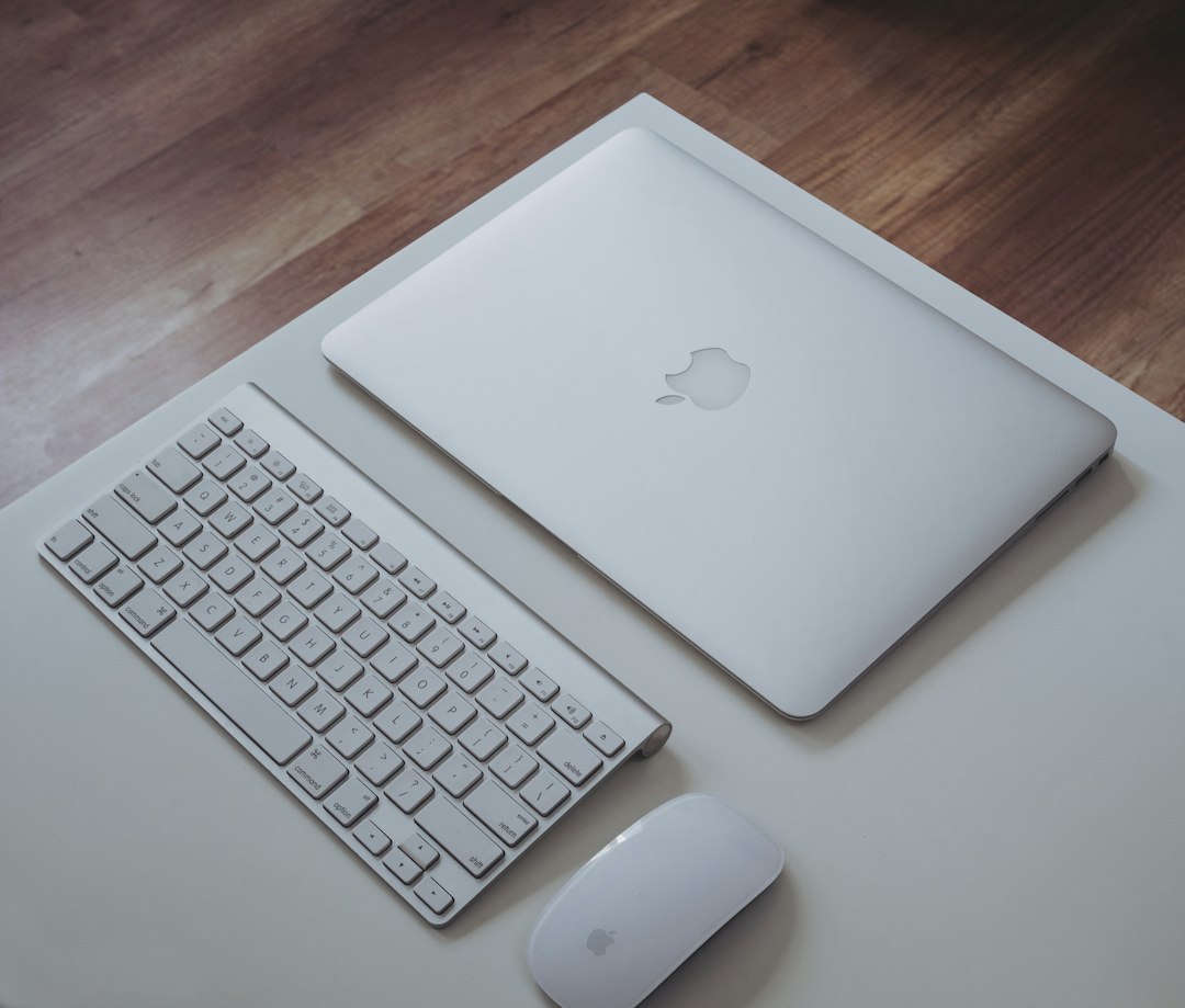 Apple-Notebook mit Tastatur und Maus auf einem Schreibtisch